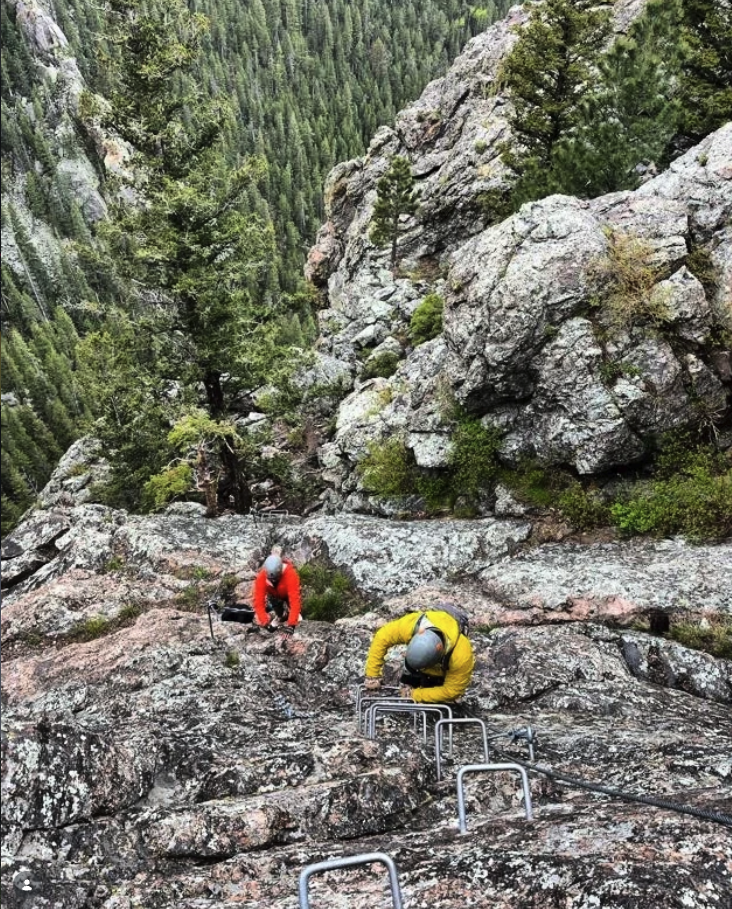 Climbers moving up rock with fixed metal rungs